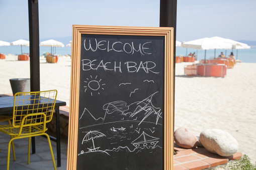 Welcome to beach bar - black board with text on the beach