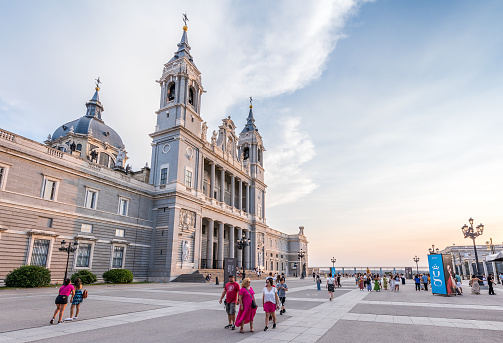 Madrid, Spain - June 26, 2023: Tourists walk at sunset in front of the Cathedral of La Almudena, in Madrid. Almudena Cathedral (Santa María la Real de La Almudena) is a Catholic church in Madrid, Spain. It is the seat of the Roman Catholic Archdiocese of Madrid.