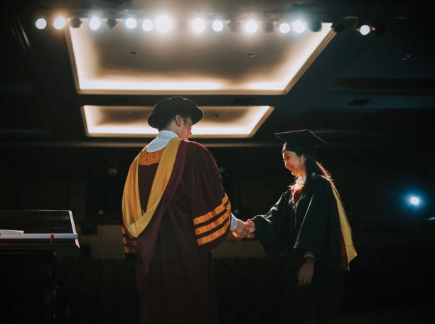 istock Convocation ceremony Asian Graduation university female student handshake with Dean on Auditorium stage 1519542511