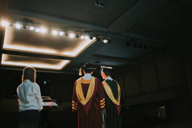 istock Convocation ceremony rear view Asian Graduation university student together with Dean standing on stage for photograph session in a row 1519542514