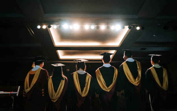 Convocation ceremony rear view Asian Graduation university students together with Dean standing on stage for photograph session in a row