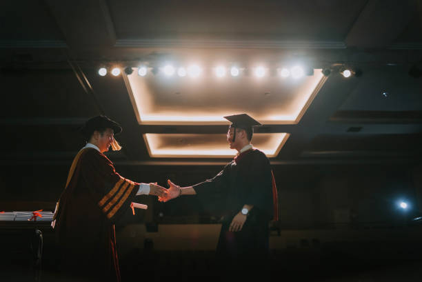 istock Convocation ceremony Asian Graduation university student handshake with Dean on Auditorium stage receiving certificate 1519542539