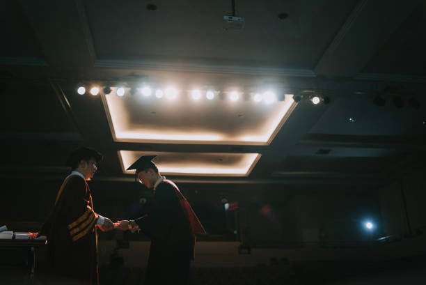 istock Convocation ceremony Asian Graduation university student handshake with Dean on Auditorium stage receiving certificate 1519542966
