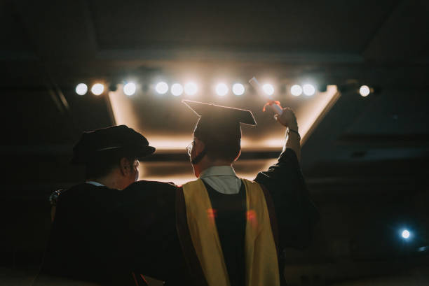 istock Convocation ceremony Excited Asian Graduation university student arm raised standing beside Dean after received Graduation Scroll on Auditorium stage 1519543142