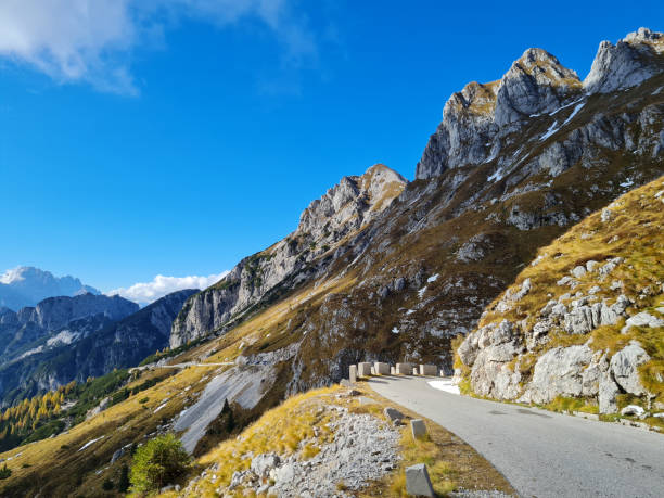 istock Alpine road over meadows under rocky peaks 1519544825