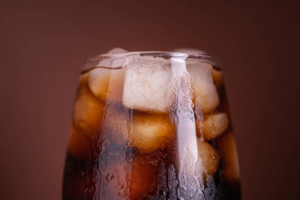 istock Cola with ice. Fresh cold sweet drink with ice cubes. Over brown background with copy space. Cola with ice. Fresh cold sweet drink with ice cubes. 1519546631