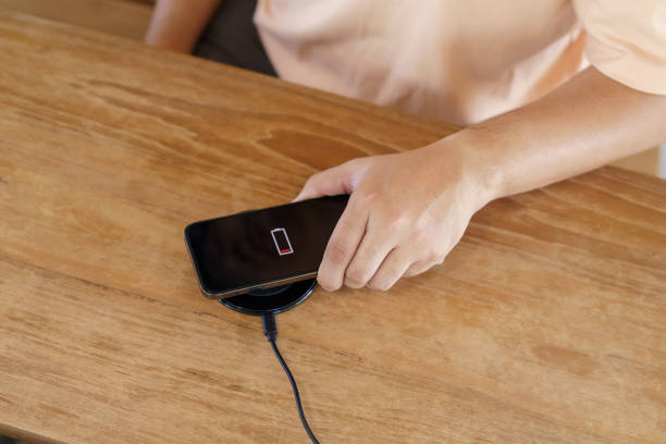 istock Charging mobile phone battery with wireless charging device in the table. Smartphone charging on a charging pad. Mobile phone near wireless charger Modern lifestyle technology concept. 1519625518