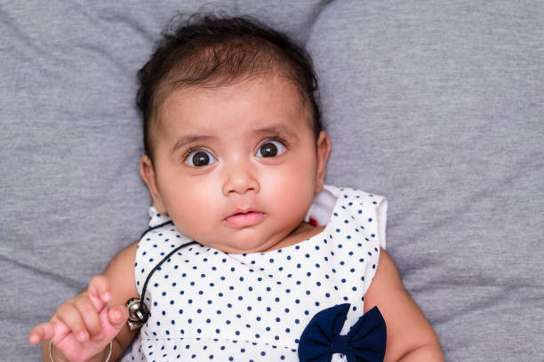 Closeup shot of Cute little newborn baby on bed looking into camera. New born baby with face expression.