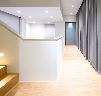 Hallway of modern interior home office with grey curtain, birch wood floor. Ceiling lights make the floor bright and glow, earth-tone color materials.  Minimal concept.