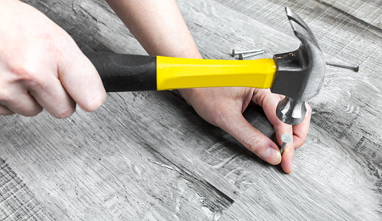 Handyman repair flooring work with yellow steel hammer and sharp nails, DIY project of home maintenance and improvement concept. A person's indoor activity for house renovation. Top view.