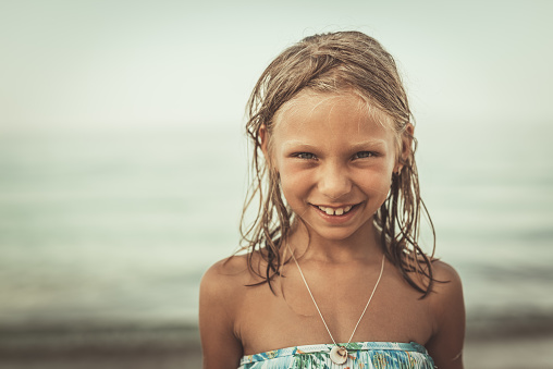 Portrait of a Cute little girl is enjoying on the beach. She is poosing and looking at camera with smile on her face.