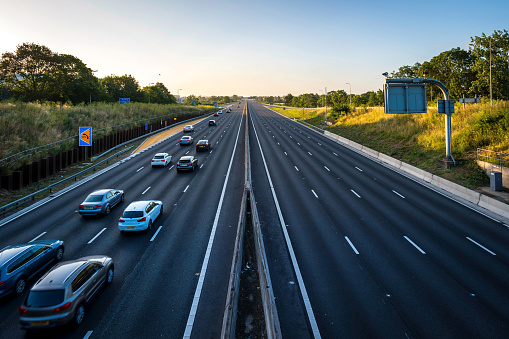 heavy car traffic moving at speed on uk motorway in england at sunrise with one line empty.