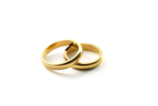 Detail of overlapping gold engagement rings on white isolated background. Elevated view.