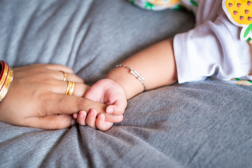 Toddler holding her mother hand closeup, New born baby holding her mother's hand