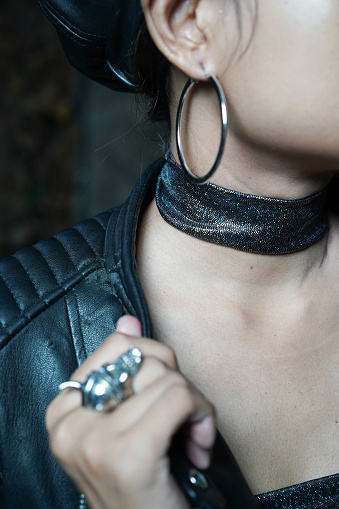 Woman use Black leather chocker, hoop earrings, skull ring, leather jacket, leather hat close up