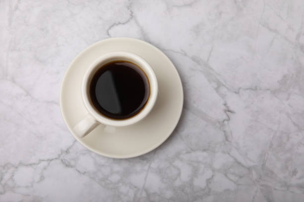 istock Hot coffee in a white coffee cup on a white texture table in a light atmosphere.Hot warming drink concept.Copy space.Top view.Place for text. 1519945929