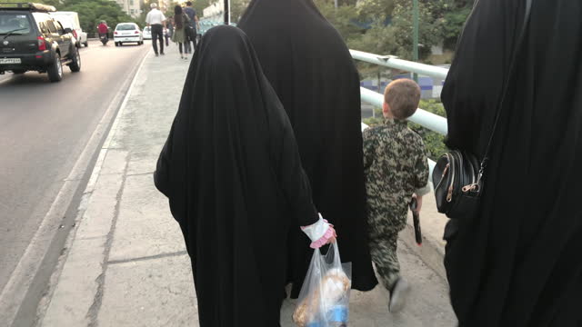 Family walking with a child dressed in Military clothes and his toy gun