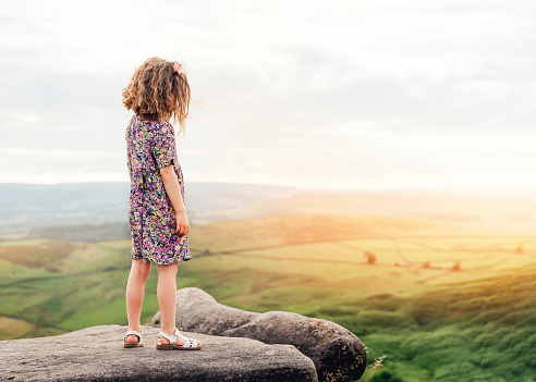 curly-haired girl standing on a rock in the Peak District