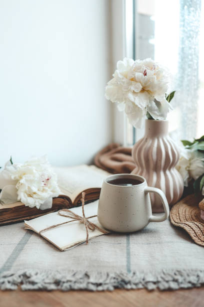 istock Cup of tea, straw hat, open book and peonies, spring still life 1519976915