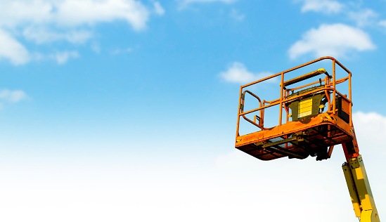 Orange telescopic boom lift on blue sky background delivered to constraction site