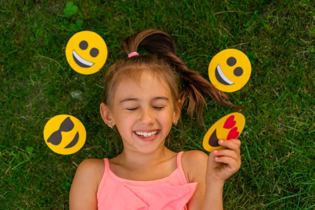 Teen laughs, squinting eyes with pleasure, surrounded by a variety of emojis A teenage girl laughs loudly, squinting her eyes with pleasure, surrounded by a variety of emojis with different emotions world laughter day stock pictures, royalty-free photos & images