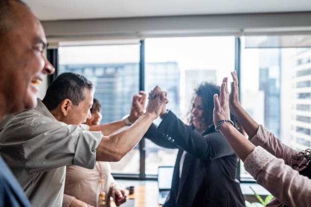 Coworkers celebrating with intertwined hands at office