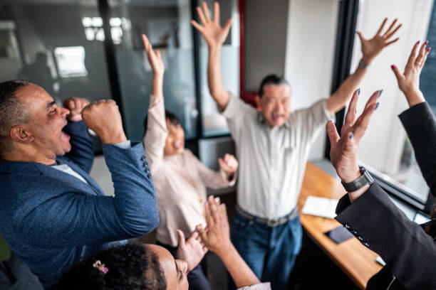 Coworkers celebrating with arms raised at office