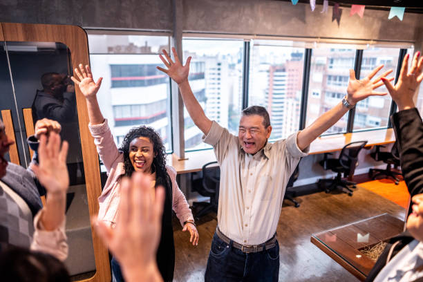 istock Coworkers celebrating with arms raised at office 1520148875