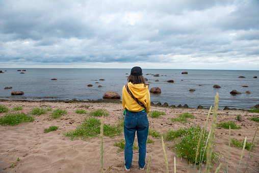 Young girl looking at the sea on the sandy shore