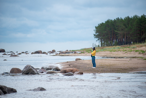 Young girl with smartphone on the sandy shore sea