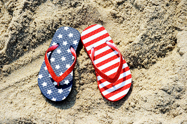 Pair of flip-flop with USA flag pattern Pair of flip-flops with USA flag pattern placed on sand usa flag shoes stock pictures, royalty-free photos & images