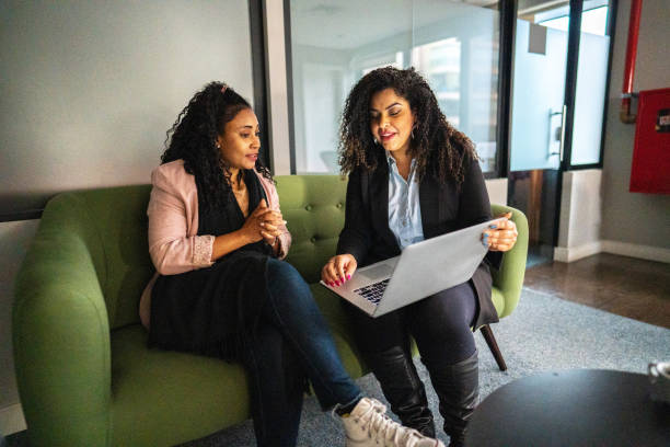 Businesswoman talking/explaining to her coworker while using laptop at office