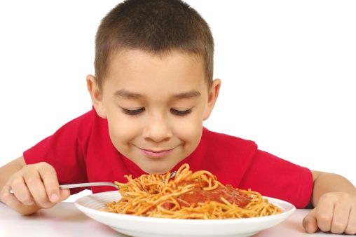 six year old boy ready to eat a full plate of spaghetti with pasta sauce, isolated on white background