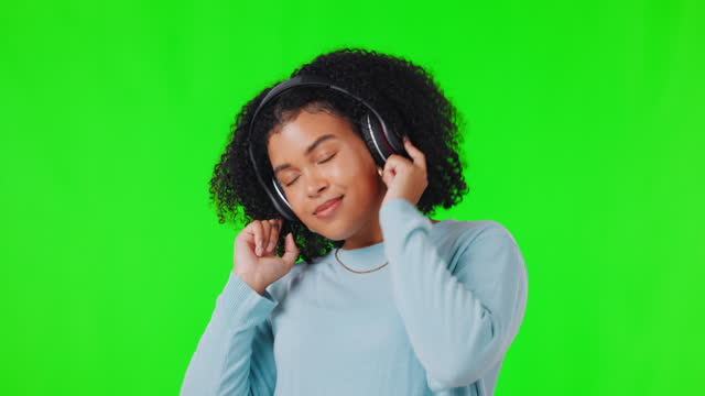 Headphones, woman and dance to music on green screen with happiness, energy and subscription. African female person on a studio background dancing and listening to audio or radio for fun and freedom