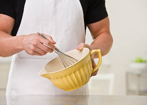 Cropped image of a white muscular male with whisk and bowl. Horizontal.