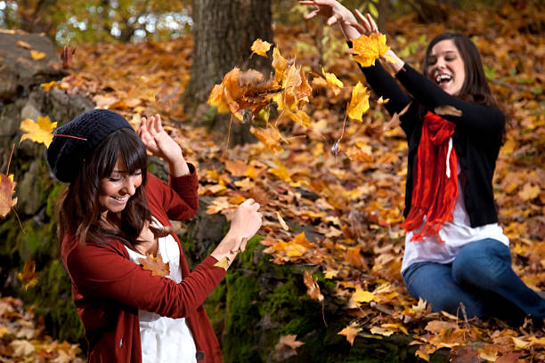 Two Girls Throwing Leaves stock photo