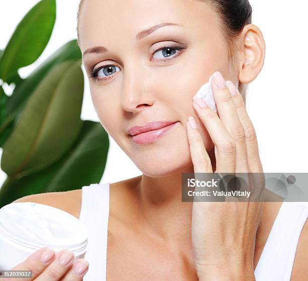 Woman Holding Moisturizer Cream And Applying It On Her Face Stock Photo - Download Image Now