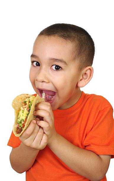 kid with a taco six year old hispanic boy ready to eat a traditional Mexican taco, isolated on white background crew cut stock pictures, royalty-free photos & images