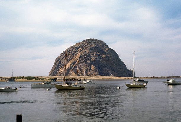 Boats moored in Morro Bay, circa 1974 A tranquil bay with several boats anchored in front of the majestic Morro Rock on the central California coast. hearkencreative stock pictures, royalty-free photos & images