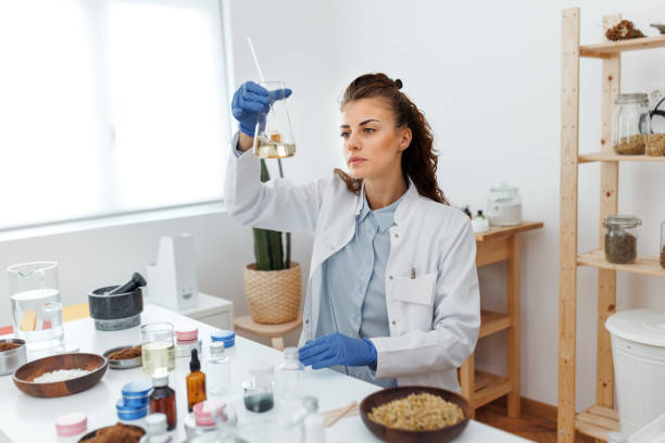 Young beautiful woman in lab coat working at her organic cosmetic workshop