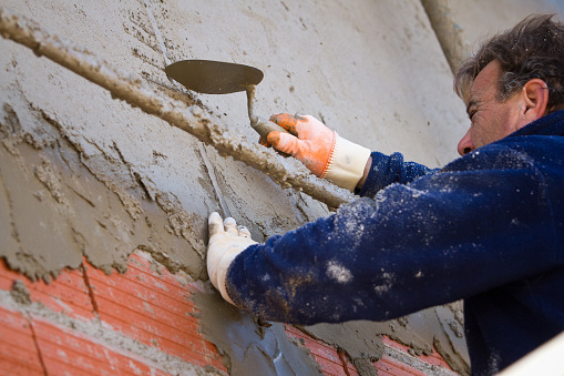 Construction worker placing cement with a trowel on the wall - Buenos Aires - Argentina