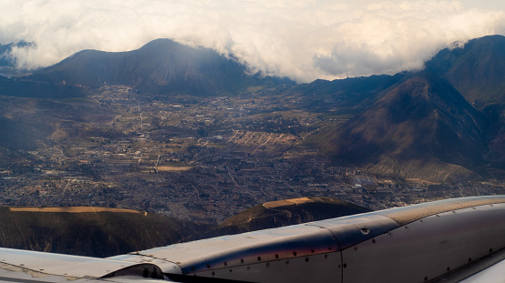 Aerial view from a passenger plane looking down toward a village nestled in an Andes Mountain valley.