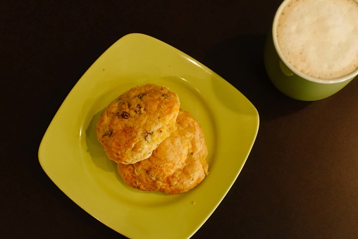 Bakery items, sweet scones, plated on lime green plate with a cup of coffee.