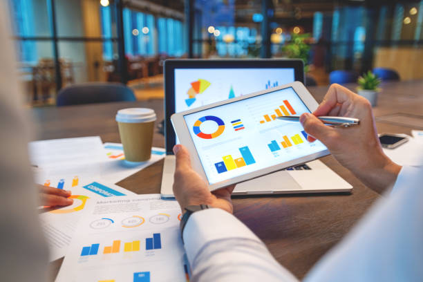 istock Two business men working on a laptop and digital tablet with financial charts, graphs and data in the office. 1520367279