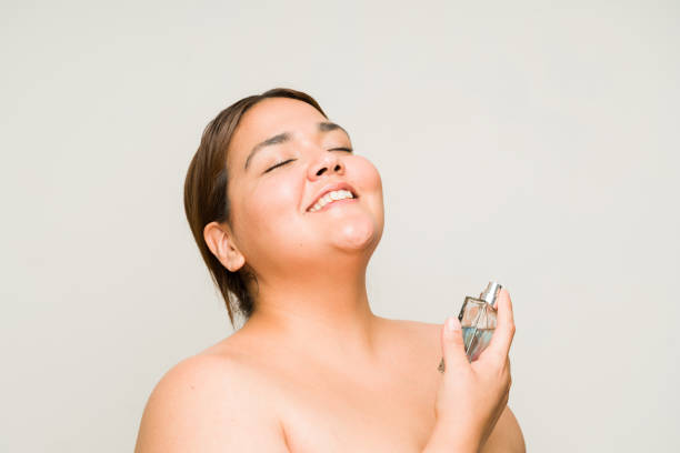 Plus size hispanic woman using fragrance spray