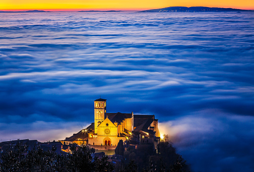 A unique day, when I found the Basilica of St. Francis of Assisi engulfed in dense fog. I waited for the arrival of the Blue Hour to have this color in the mist. In the distant background, you can see the city of Perugia