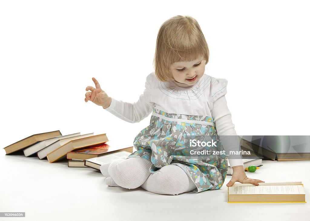 The baby girl sitting among books The little girl sitting among books and turning over the pages; white background 2-3 Years Stock Photo