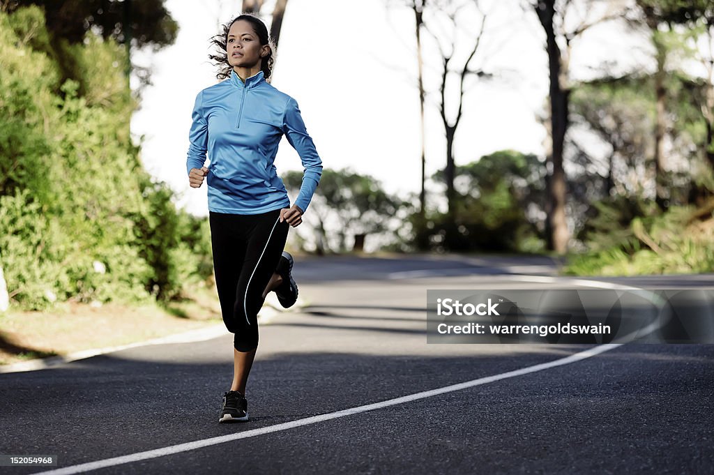 Female athlete running in the street portrait of a healthy woman training for running along a mountain road alone. fitness wellness athlete Active Lifestyle Stock Photo