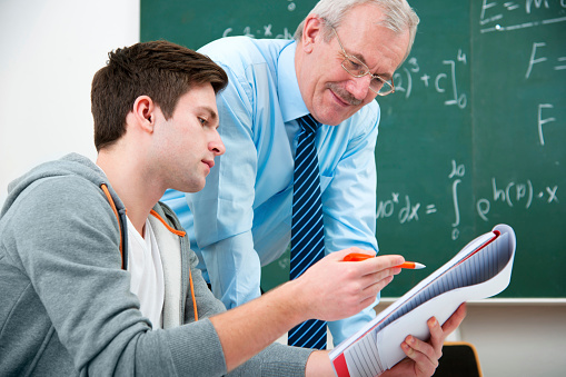 male student with a teacher in classroom