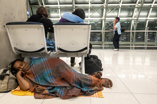 Bangkok, Thailand May 31, 2023 An Asian man sleeps on the floor in the airport terminal.